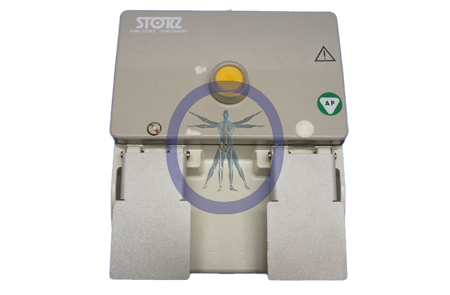 A Karl Storz 20012630 Two Pedal Two Stage Foot Switch, rectangular, with a central emblem of a human figure surrounded by a blue circle, and labeled buttons on a metallic surface.